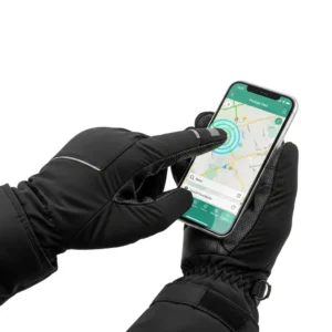 A hand wearing a heated snowmobile glove interacting with a smartphone touchscreen, illustrating the touch-sensitive fingertip feature.
