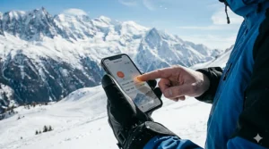 An illustration of a skier using a smartphone with the touchscreen-compatible fingertips of their heated alpine gloves.