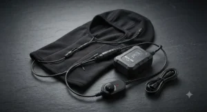 Rechargeable battery pack and controller connected to a heated motorcycle helmet liner on a dark background