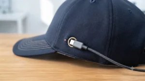 A USB cable connected to a wall adapter charging a heated golf cap.
