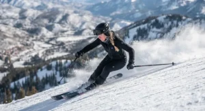 An active skier making a sharp turn on a downhill run, showcasing the flexibility of a battery heated body suit for skiing.