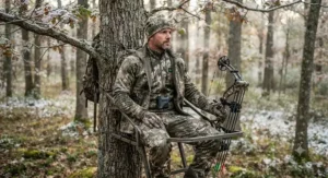 Hunter in camouflage gear wearing a slim-profile battery heated body suit in a tree stand